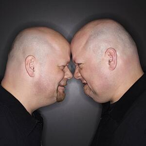 Bald mid adult identical twin men standing face to face with angry expression.