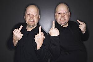 Bald mid adult identical twin men making obscene gesture at viewer.