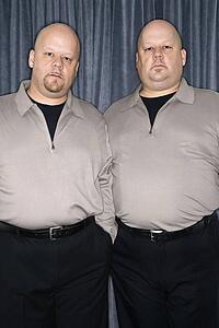 Bald identical twin mid adult men standing together looking at viewer.