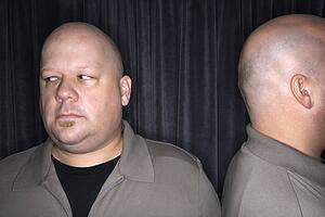 Mid adult bald man looking away from his identical twin.