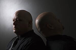 Bald identical twin men standing back to back