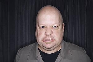Mid adult bald man looking at viewer with angry expression.