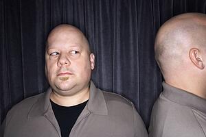 Bald man looking to side at his identical twin