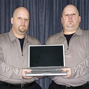 Bald identical twin men holding a laptop computer and looking at viewer.