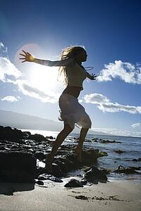 Young adult Asian Filipino female jumping on beach 