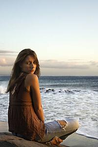 Portrait of sexy young woman sitting on beach looking over her shoulder 