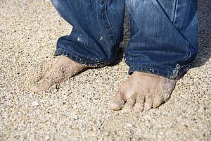 Male feet in jeans on sandy beach