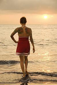 Attractive tattooed Caucasian woman on beach at sunset 