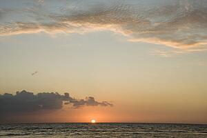 Sun rising over horizon of ocean