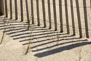 Close-up of fence and shadows on beach Bald Head Island, North Carolina.