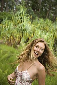Beautiful happy Caucasian young adult woman in lush forest smiling and looking at viewer.
