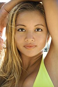 Beautiful young adult Asian Filipino female in swimsuit looking at viewer with arms raised 