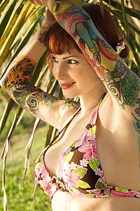 Portrait of sexy Caucasian redheaded woman in bikini with palm tree 