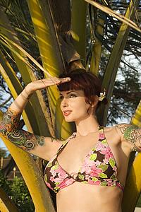 Portrait of sexy redheaded woman in bikini with palm tree 