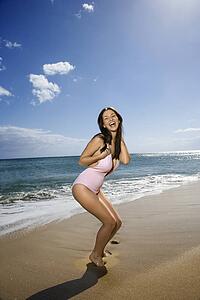 Pretty smiling young Caucasian woman in swimsuit having fun at beach 