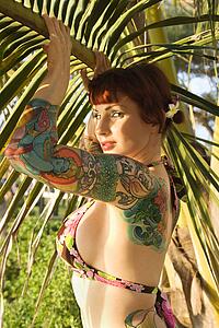 Portrait of sexy Caucasian redheaded woman in bikini with palm tree 