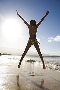 Girl in bikini jumping on beach 