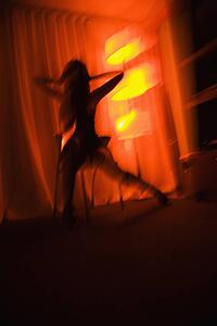 Blurred pretty young woman silhouetted by floor lamp