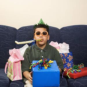 Boy with birthday party favors and presents looking at viewer