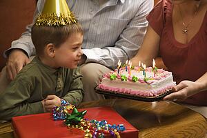 Boy in party hat with Birthday cake and family