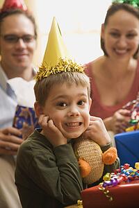 Caucasian boy at birthday party looking at viewer making facial expression.