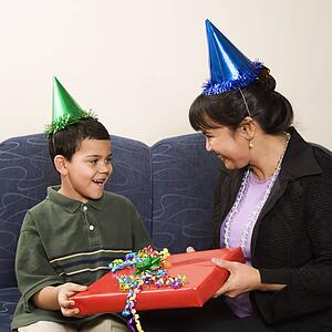 Mother giving present to surprised son at birthday party