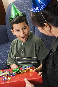 Mother giving present to surprised son at birthday party