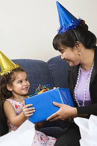 Mother giving daughter present at birthday party