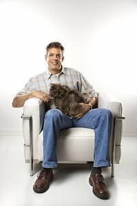 Mid-adult Caucasian man sitting holding Persian cat.