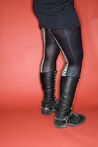 Portrait of woman's lower body wearing leggings and boots against orange background