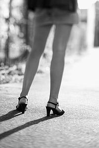 Rear view of woman's legs while she stands on a street