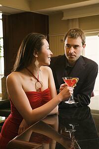 Woman and man at bar toasting martinis