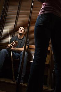 Young man with billiards cue looking at woman standing before him.