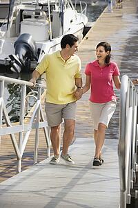 Mid-adult couple holding hands and walking up ramp at harbor