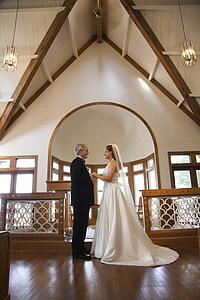 Portrait of bride and groom holding hands at the alter of a church
