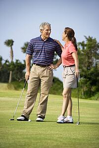 Man and woman standing on golf course talking to each other