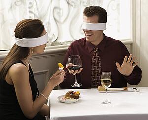 Couple dining in a restaurant with blindfolds over eyes