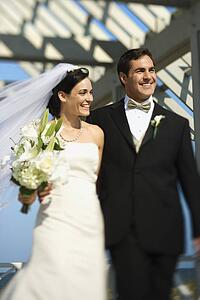 Caucasian mid-adult bride and groom walking together smiling.