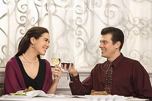Couple smiling and toasting wine glasses in restaurant