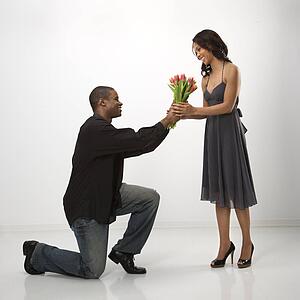 Man on knees giving woman flowers