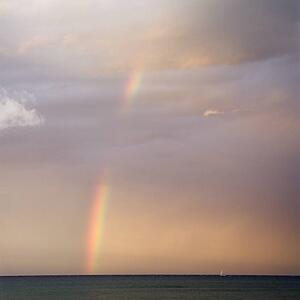 Rainbow spreading across sky on coast