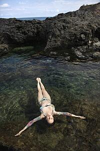 Sexy Caucasian woman in bikini floating in tidal pool 