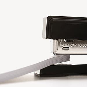 Close up of black stapler on white background stapling paper