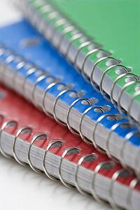 Close up of three spiral bound notebooks stacked up.