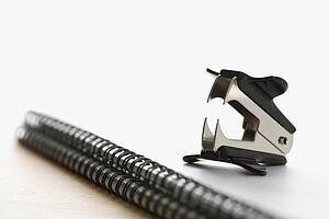 Black staple remover on top of a spiral bound notebook