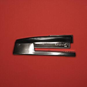 Black stapler on red background.