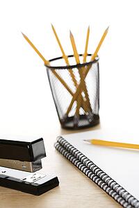 Pencils, a stapler, and spiral bound notebooks arranged on a desk