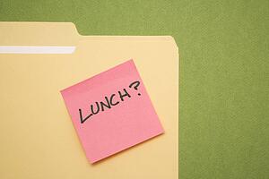 Folder with pink sticky note reading lunch on a green background