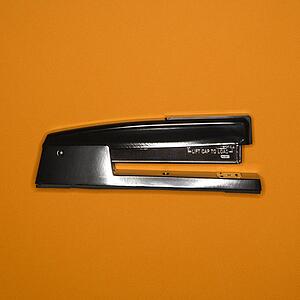 Black stapler on orange background