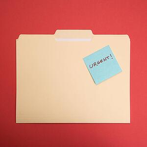 Folder with a sticky note attached reading urgent on a red background.